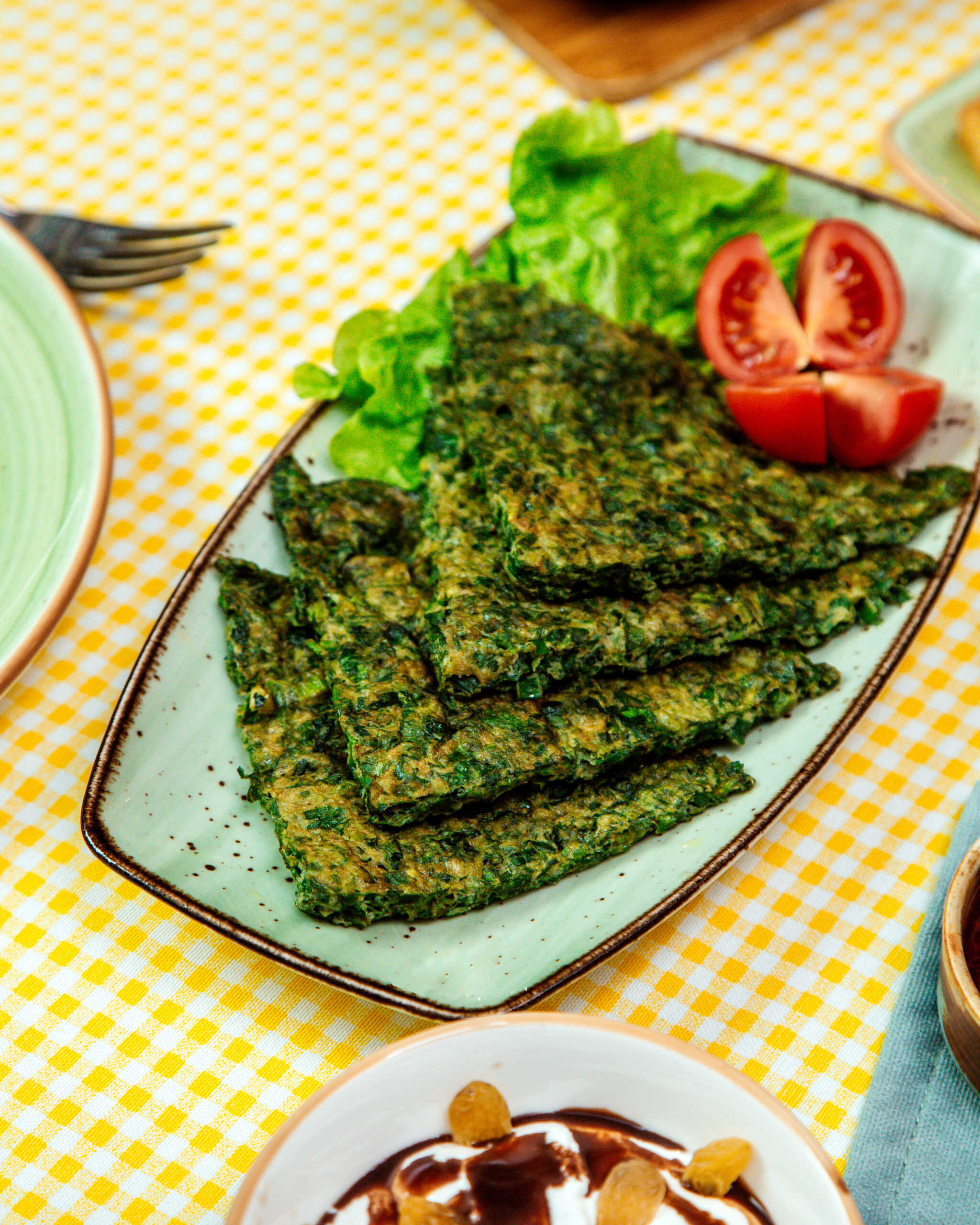 vue-laterale-des-oeufs-frits-traditionnels-azerbaidjanais-kuku-avec-plateau-herbson-avec-tomates-fraiches